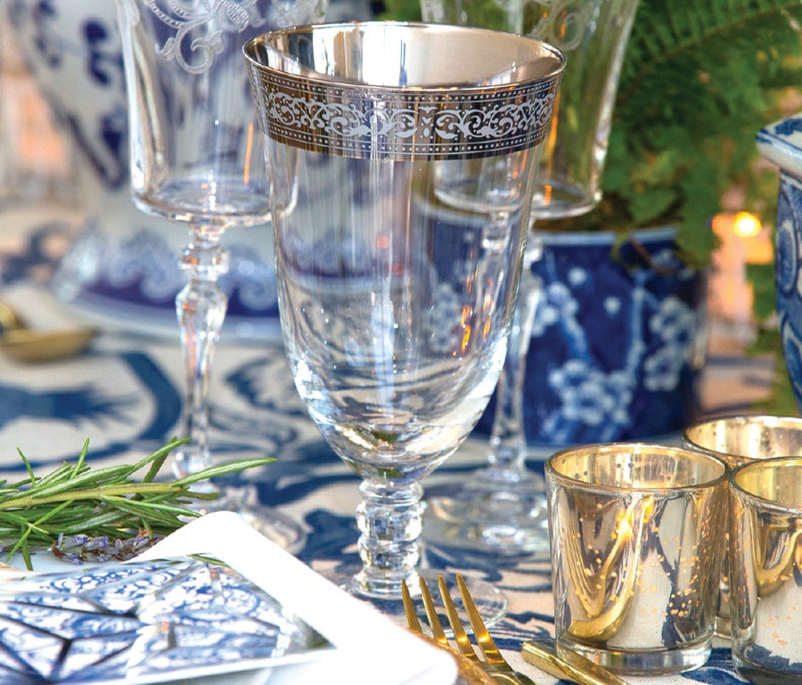 A metallic brim on a wine glass at a blue accented table setting.