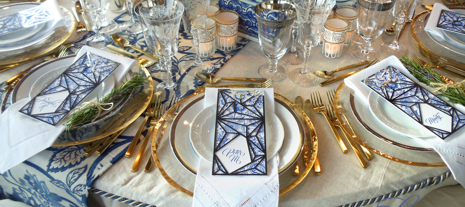 A place setting at a round table featuring gold trimmed rental plates, charger, and silverware.