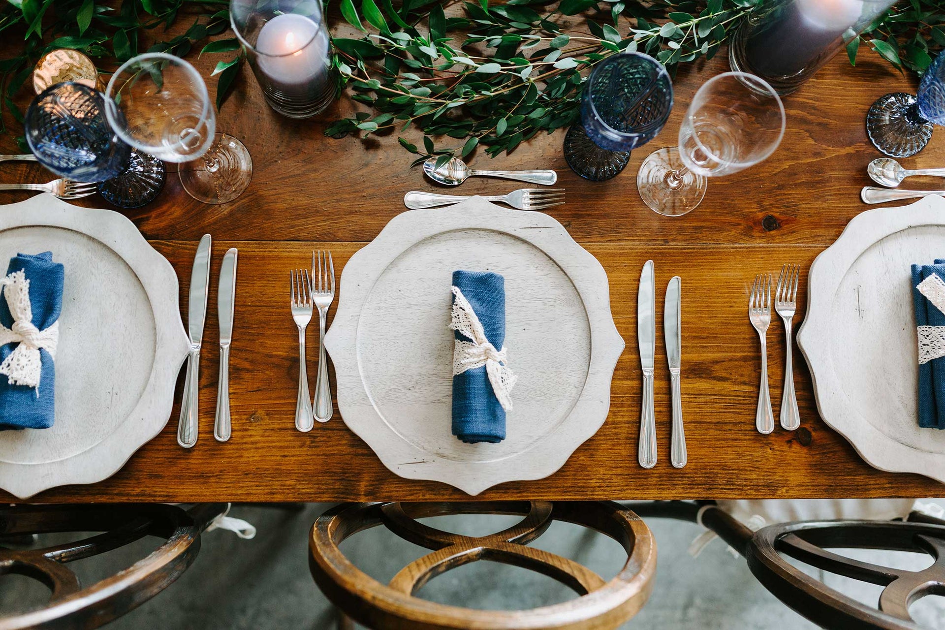 Place setting on a wooden table and blue napkin featuring rental party items.